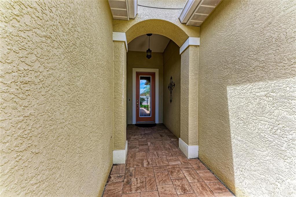 A covered entryway features a tiled floor, stucco walls, and an arched doorway with a door — 11763 FENNEMORE WAY, PARRISH, FL