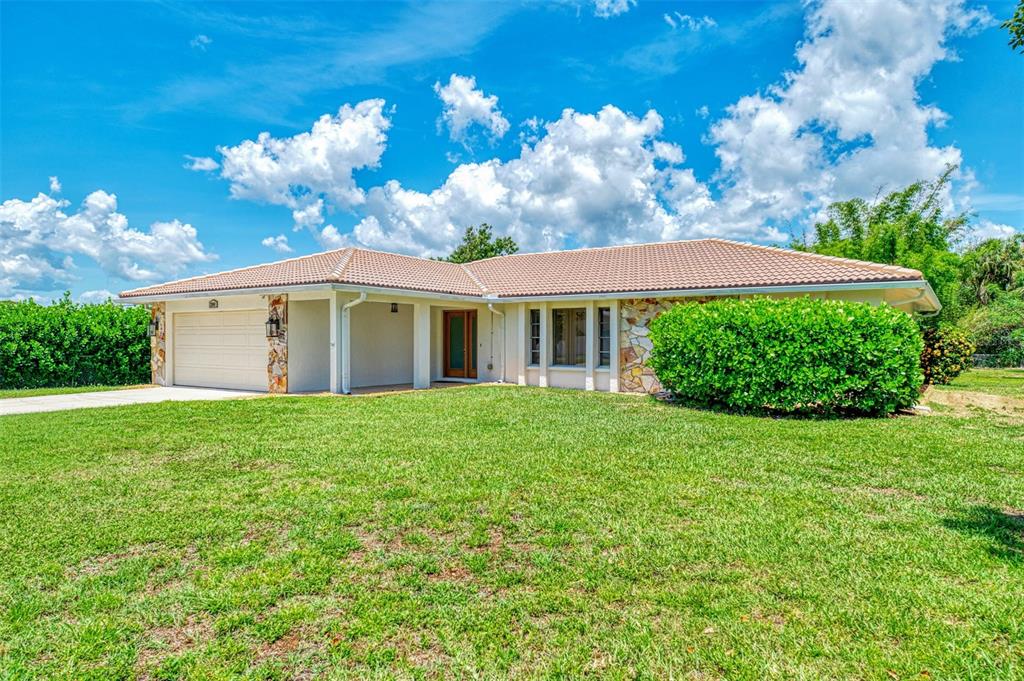 A single-story house with a tan tile roof, stone accents, and a large front lawn — 2340 PALMETTO STREET, NOKOMIS, FL