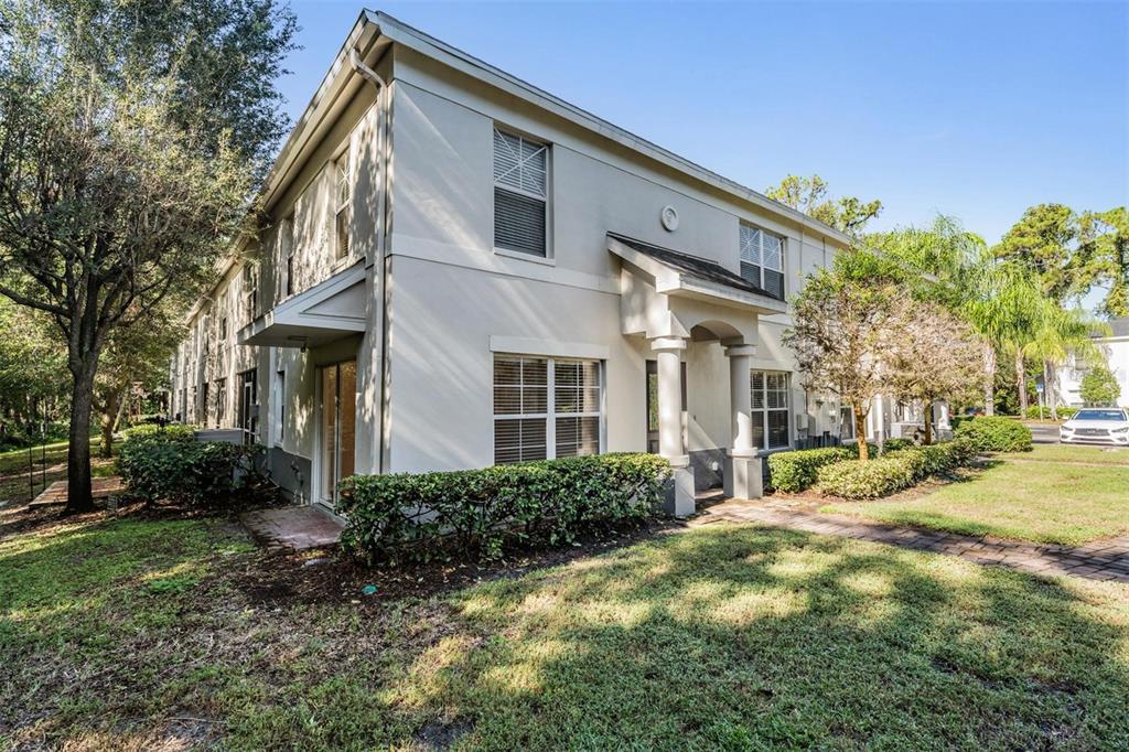 A two-story beige apartment building features a covered entryway, sliding glass doors, and landscaping — 9624 CHARLESBERG DRIVE, TAMPA, FL