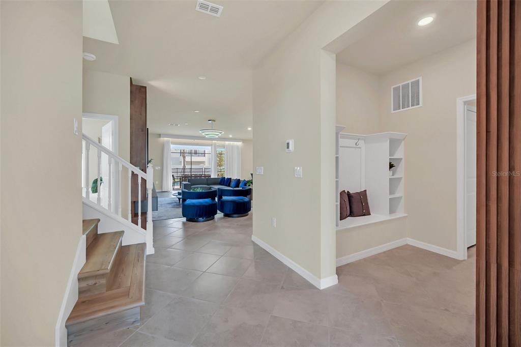 An entryway features a staircase, tile flooring, and a built-in mudroom bench with shelving — 16248 SAINT MARTIN STREET, CLERMONT, FL