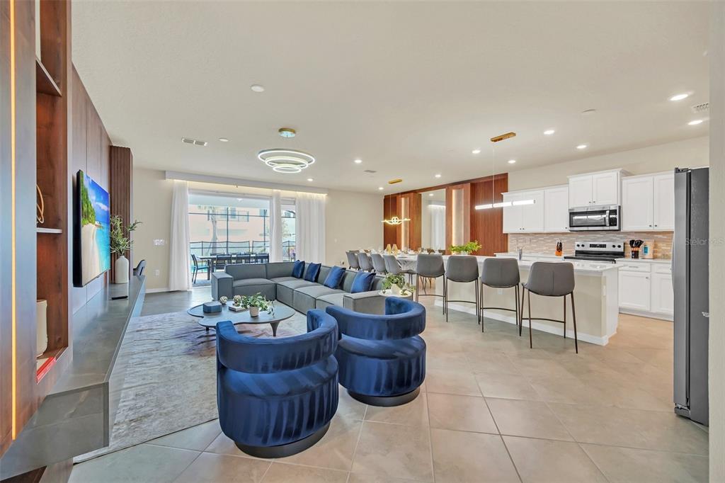 An open-concept living room and kitchen featuring blue velvet chairs, a sectional, and island seating — 16248 SAINT MARTIN STREET, CLERMONT, FL