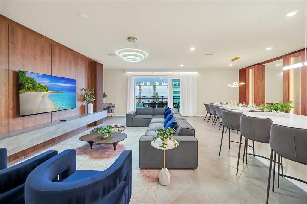 A modern open-concept living and dining area features wood paneling, a large sectional, and seating — 16248 SAINT MARTIN STREET, CLERMONT, FL