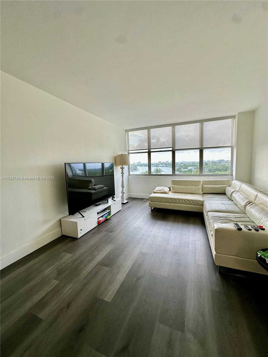 A living room features a white sectional sofa, a television on a stand, and windows — 7441 Wayne Ave # 6B, Miami Beach FL 33141, MIAMI BEACH, FL