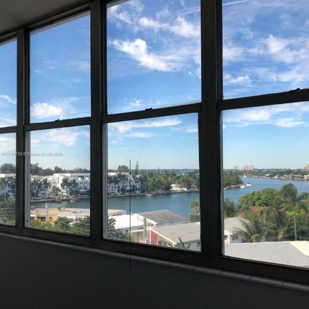 A view of a waterfront neighborhood seen through a large, multi-pane window — 7441 Wayne Ave # 6B, Miami Beach FL 33141, MIAMI BEACH, FL