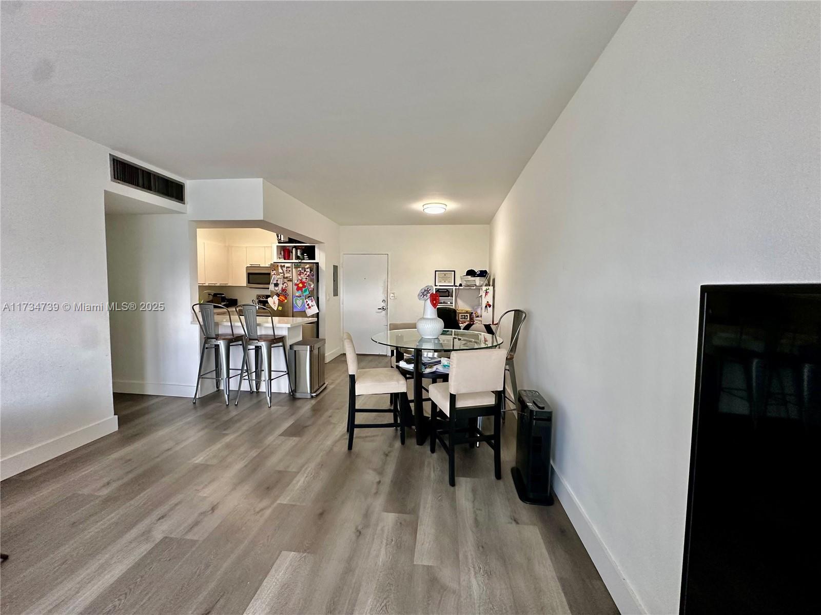 An open-concept living area features a kitchen with a breakfast bar and a dining table — 7441 Wayne Ave # 6B, Miami Beach FL 33141, MIAMI BEACH, FL