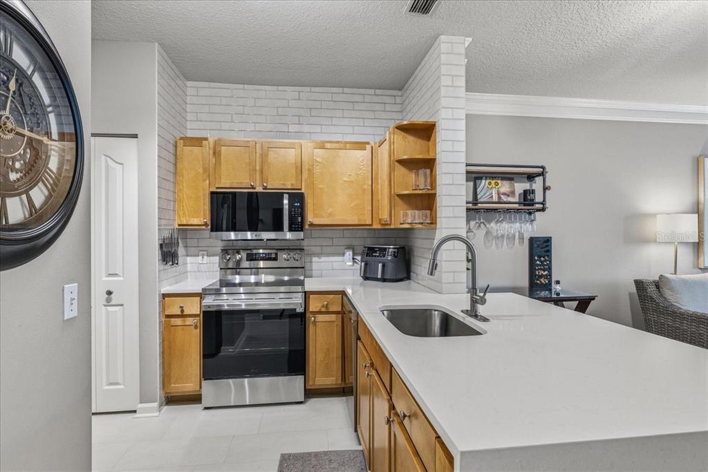 A kitchen features light wood cabinets, white subway tile backsplash, stainless steel appliances, and quartz countertops — 4207 S DALE MABRY HIGHWAY UNIT 8308, TAMPA, FL