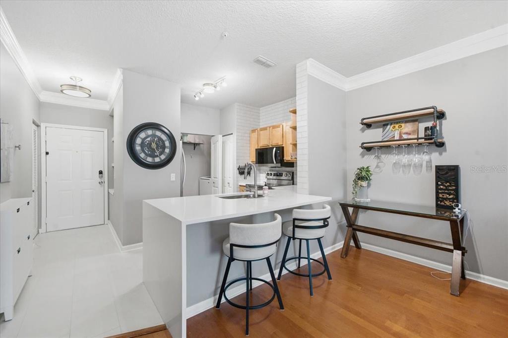 A kitchen with a white quartz island, bar seating, and a dining area with wood floors — 4207 S DALE MABRY HIGHWAY UNIT 8308, TAMPA, FL