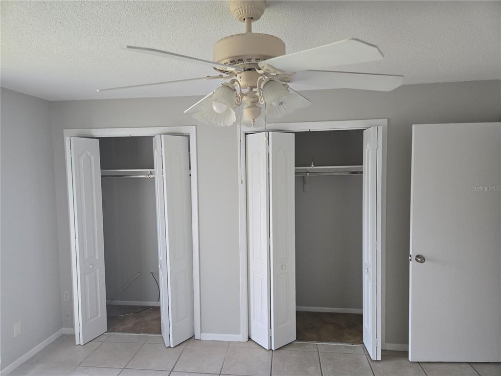 A room with light gray walls, tile flooring, a ceiling fan, and two open closets — 1935 CONWAY ROAD UNIT O5, ORLANDO, FL