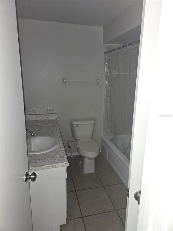 A small bathroom features a vanity with a stone-look countertop, a toilet, and a shower-tub — 1935 CONWAY ROAD UNIT O5, ORLANDO, FL