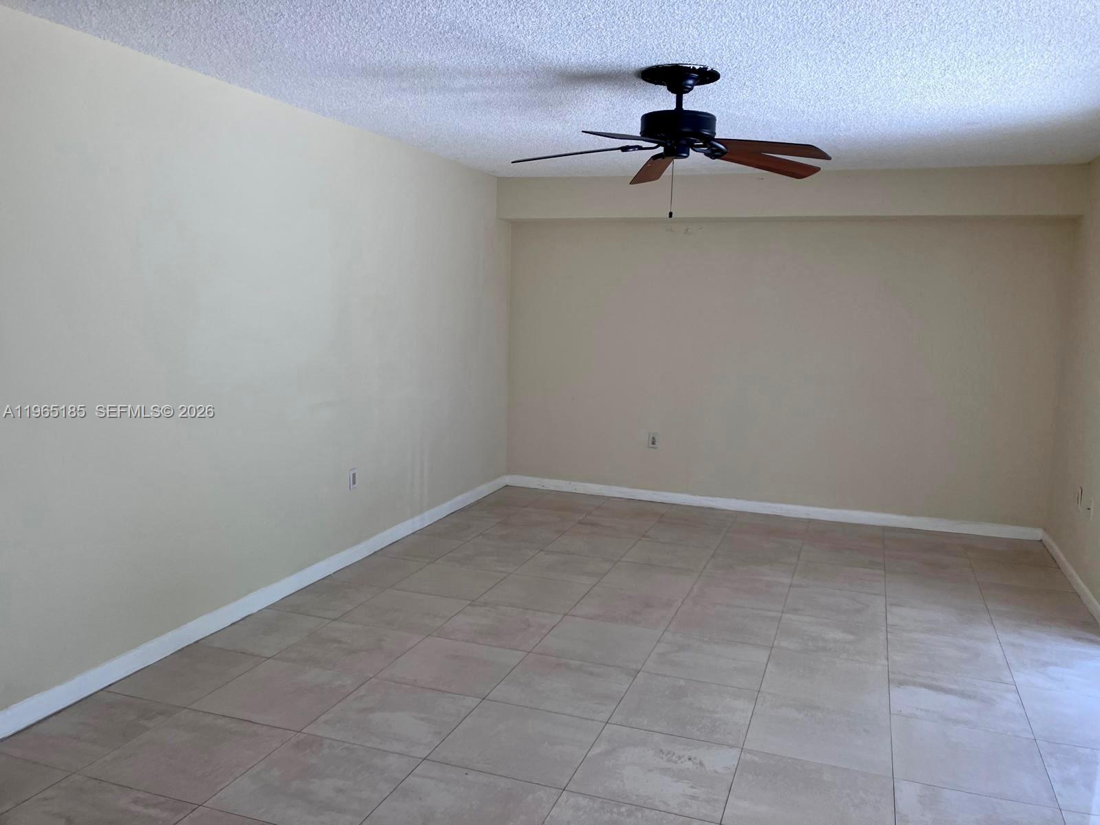 An empty room features beige walls, a ceiling fan, and light-colored square floor tiles — 2610 26th way, Riviera Beach FL 33407, RIVIERA BEACH, FL