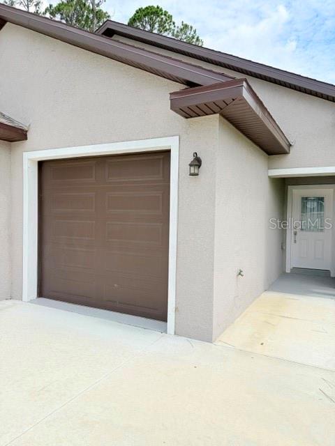 A tan stucco house exterior features a brown garage door and a white front door — 29 SLUMBER PATH UNIT B, PALM COAST, FL