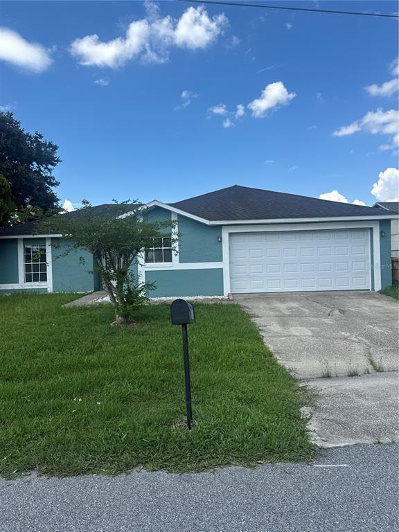A teal single-story house with a white garage door and a front lawn — 913 SAN RAFAEL WAY, KISSIMMEE, FL