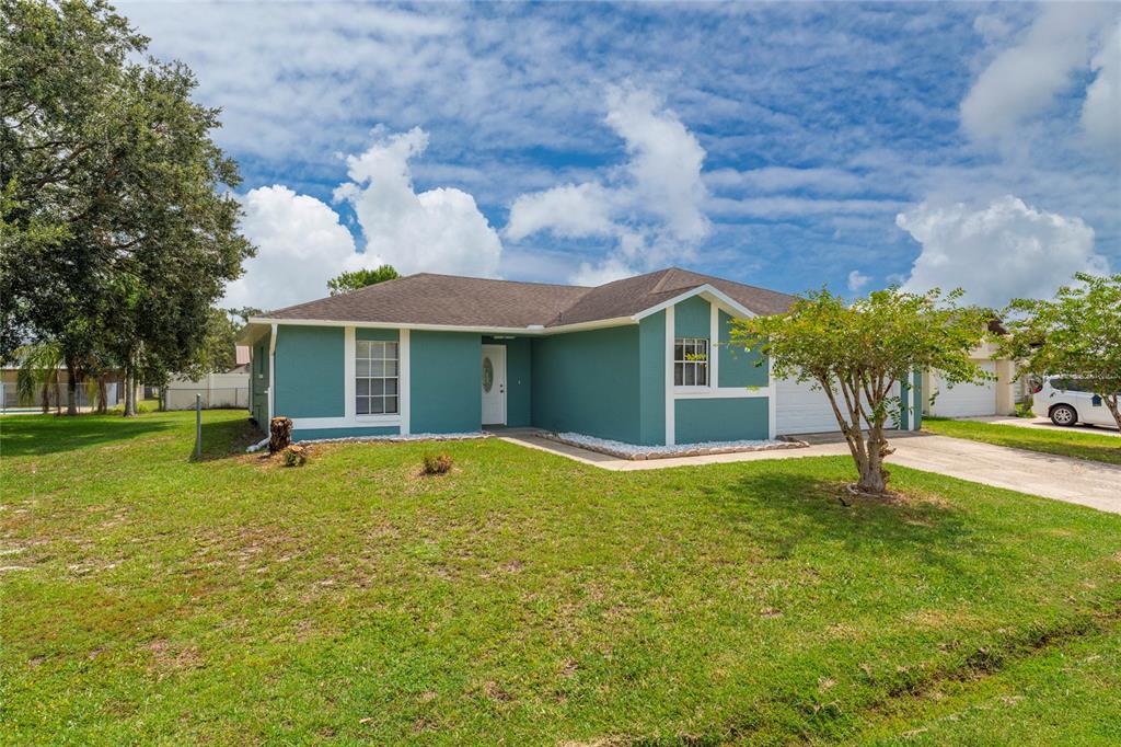 A teal single-story house with a white front door, garage, and a large front lawn — 913 SAN RAFAEL WAY, KISSIMMEE, FL