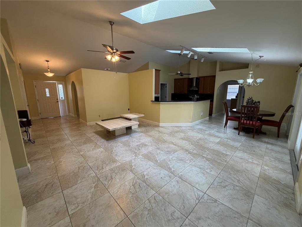 An open-concept living and dining area features tile flooring, vaulted ceilings with skylights, and lighting — 2243 BANCROFT BOULEVARD, ORLANDO, FL