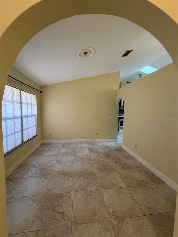 A room with beige walls, tile flooring, and an arched entryway leading to a kitchen — 2243 BANCROFT BOULEVARD, ORLANDO, FL
