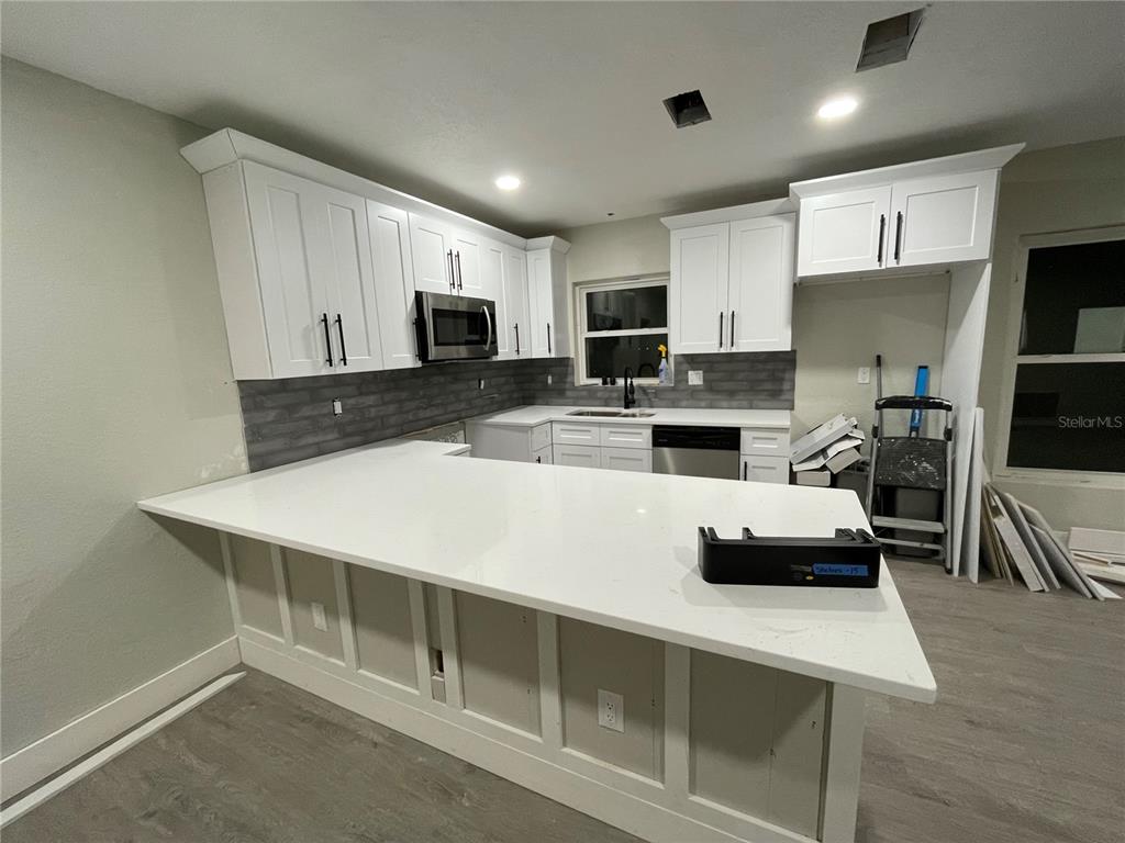 A kitchen features white cabinets, a white countertop, and a gray tiled backsplash — 2816 HARGILL DRIVE, ORLANDO, FL