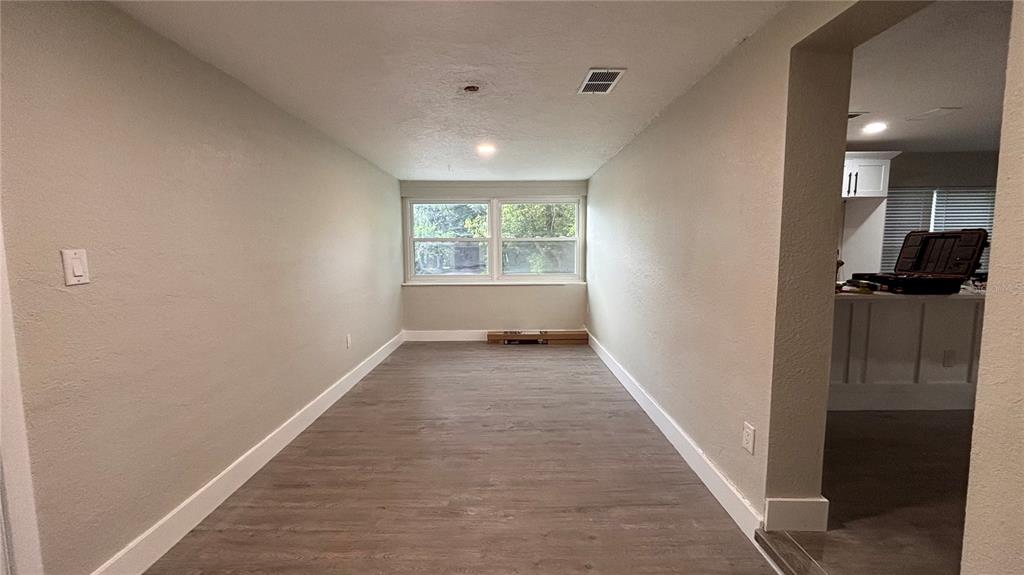 A room with light gray walls, wood-look flooring, and a window overlooking trees — 2816 HARGILL DRIVE, ORLANDO, FL