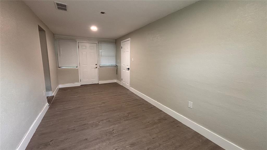An empty room features light gray walls, wood-look flooring, a white door, and white trim — 2816 HARGILL DRIVE, ORLANDO, FL