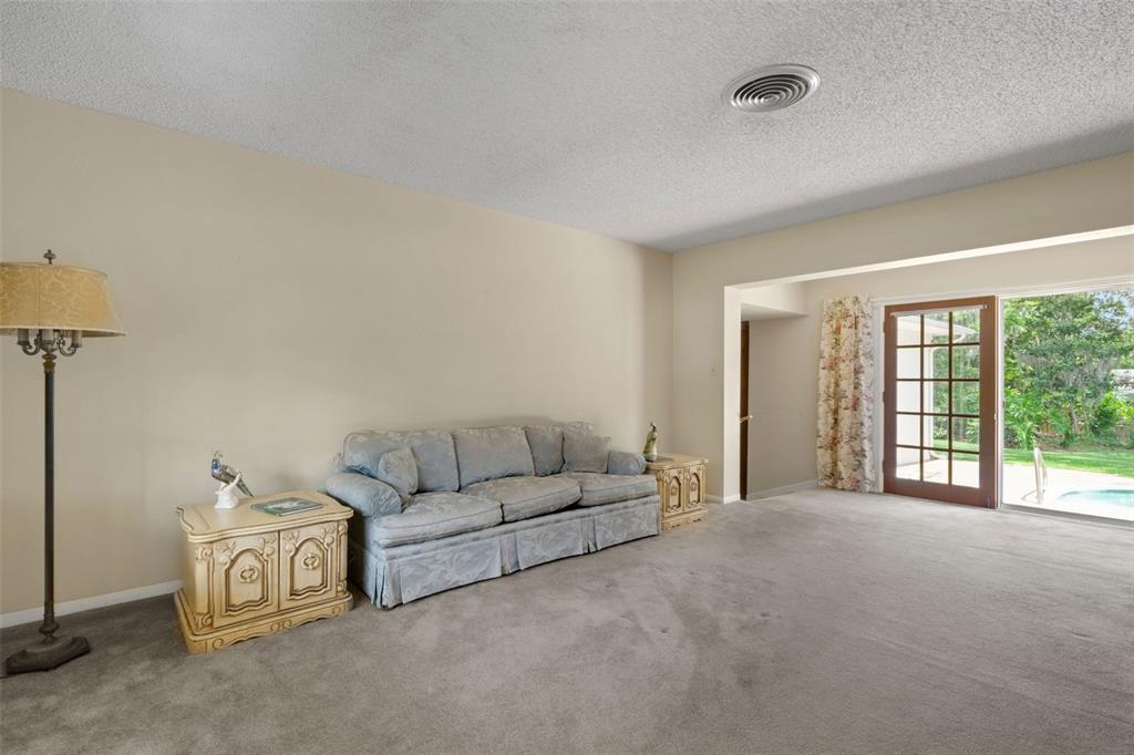 A living room with beige walls, gray carpet, a sofa, end tables, and sliding glass doors — 4200 CLEVELAND HEIGHTS BOULEVARD, LAKELAND, FL