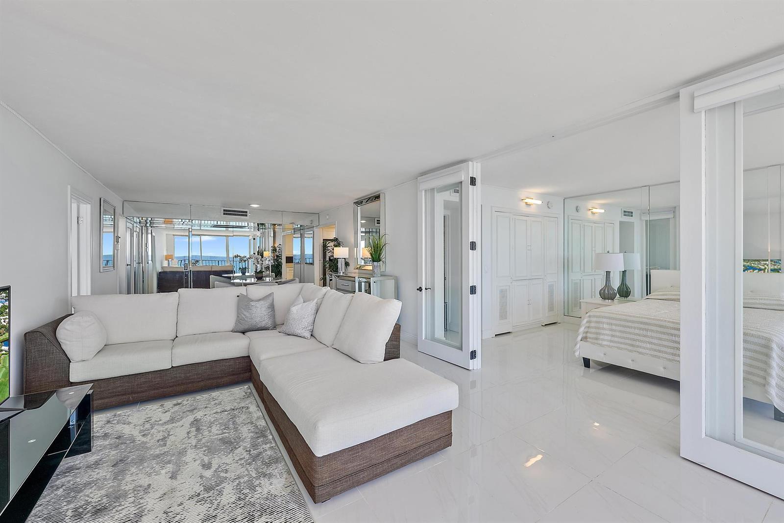 A living room with a sectional sofa connects to a bedroom through glass doors — 3456 S Ocean Boulevard # 802, Palm Beach FL 33480, PALM BEACH, FL