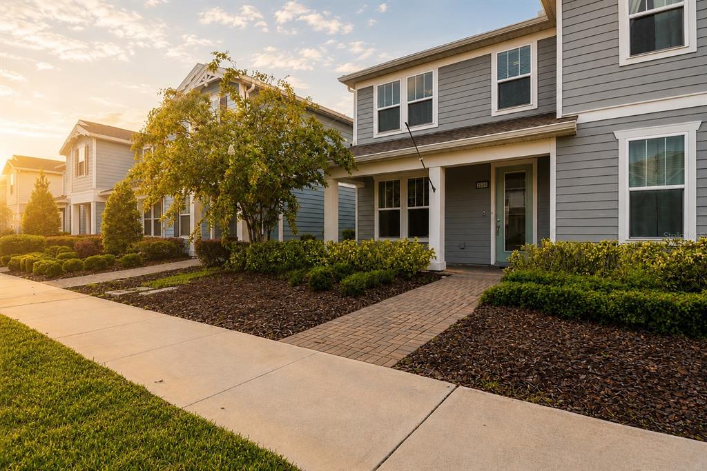 A row of two-story gray houses with front porches and landscaped yards under a sunset sky — 14557 ORCHID ISLAND DRIVE, ORLANDO, FL