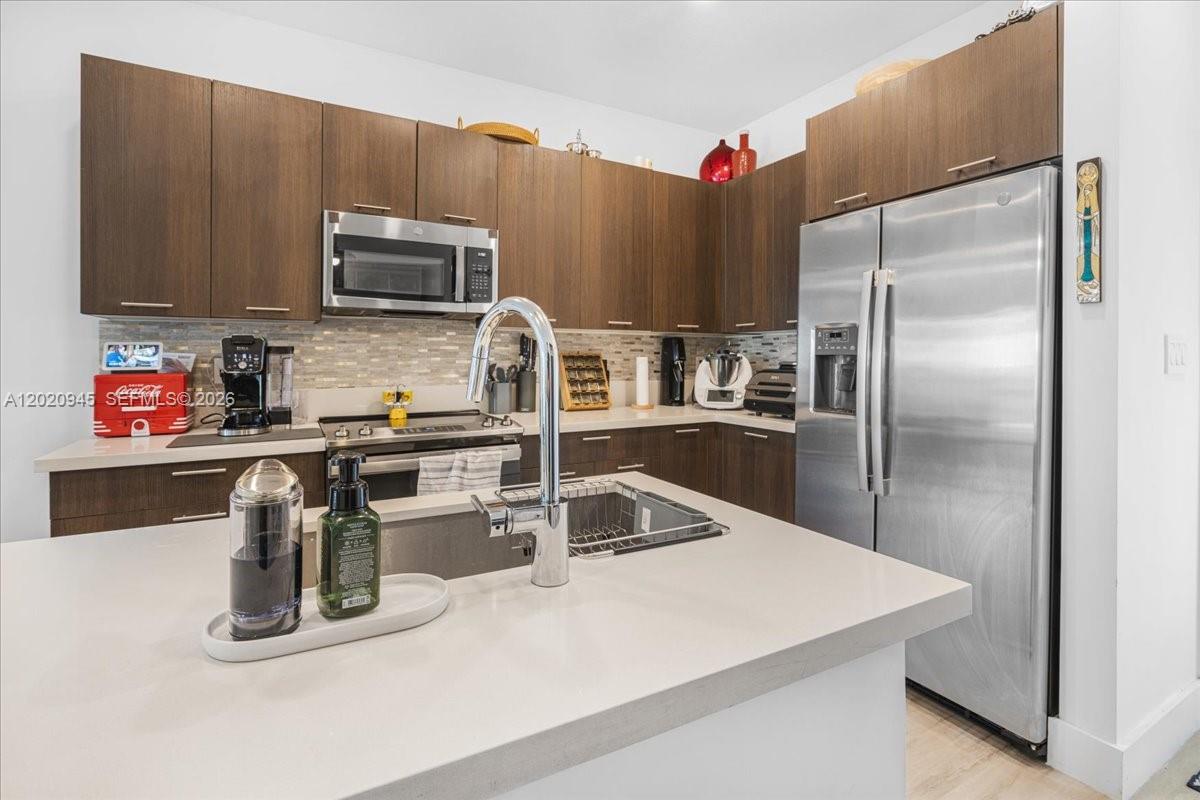 A modern kitchen features dark wood cabinets, stainless steel appliances, and a central island — 8301 NW 41st St # 309, Doral FL 33166, DORAL, FL