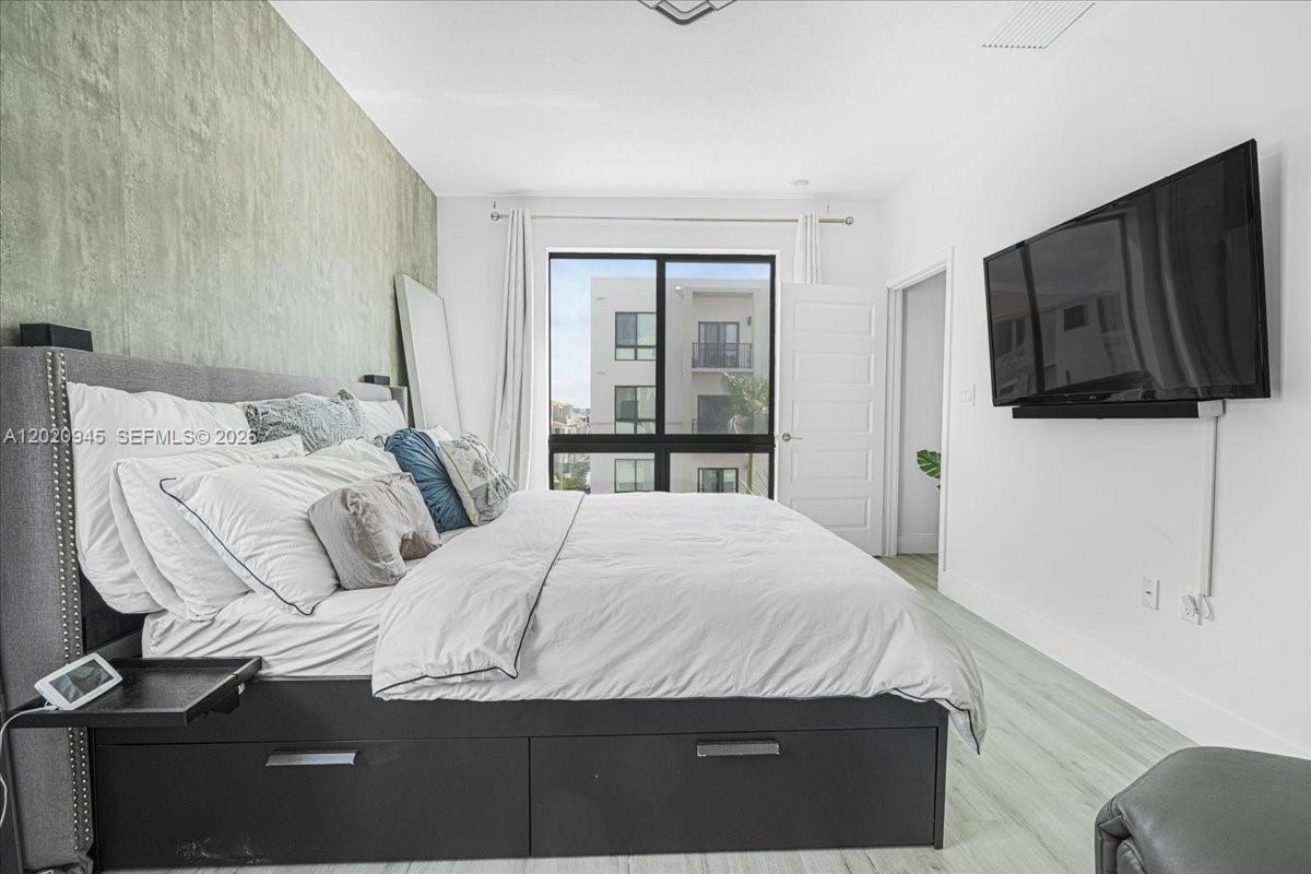 A bedroom features a platform bed, a wall-mounted television, and a large window — 8301 NW 41st St # 309, Doral FL 33166, DORAL, FL