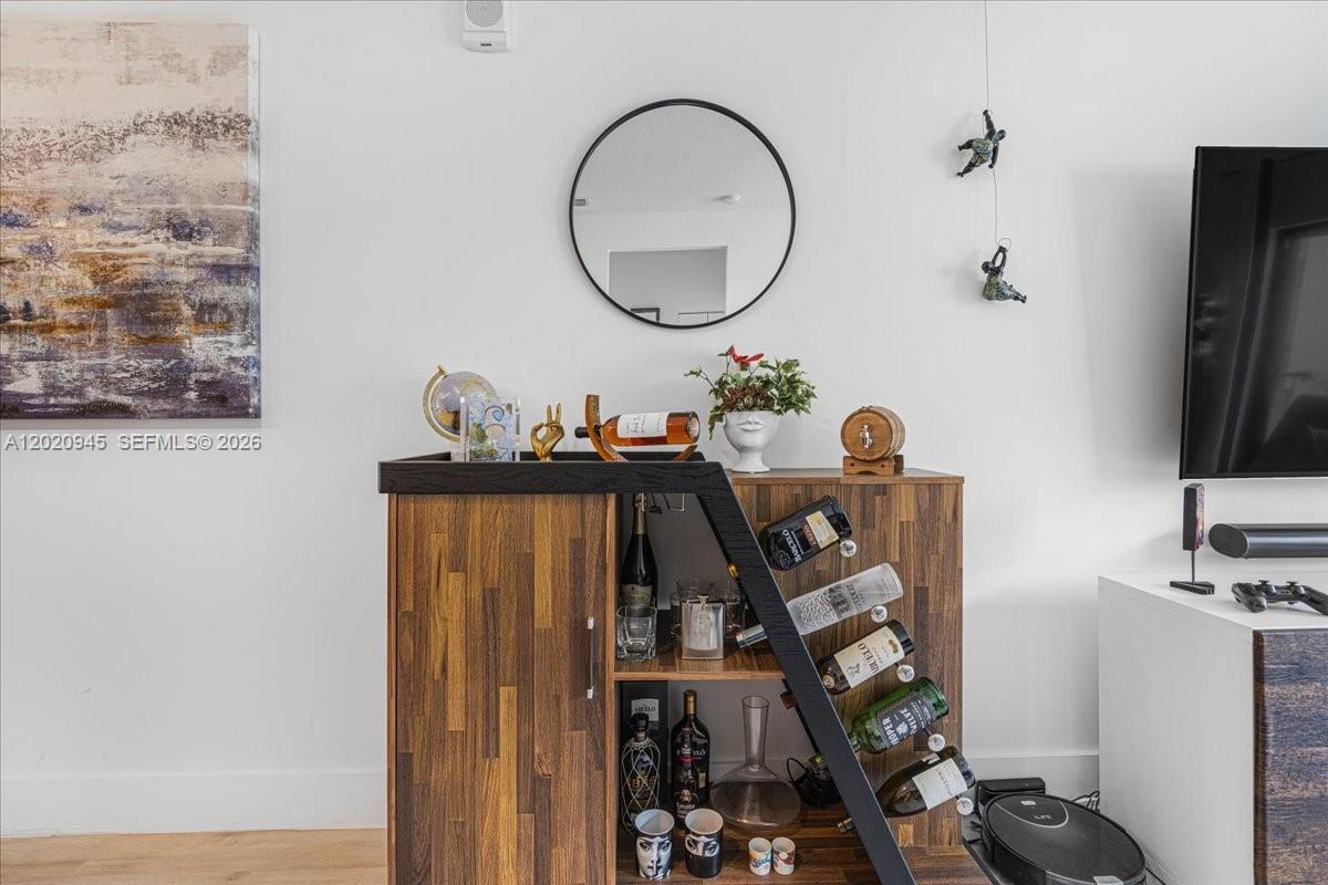 A wooden bar cabinet with wine storage sits against a white wall with decor — 8301 NW 41st St # 309, Doral FL 33166, DORAL, FL