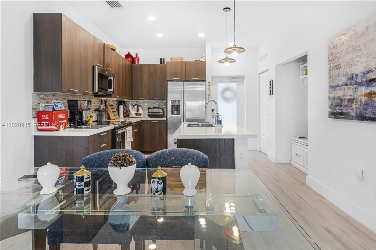 A modern kitchen features dark wood cabinetry, stainless steel appliances, and a glass dining table — 8301 NW 41st St # 309, Doral FL 33166, DORAL, FL