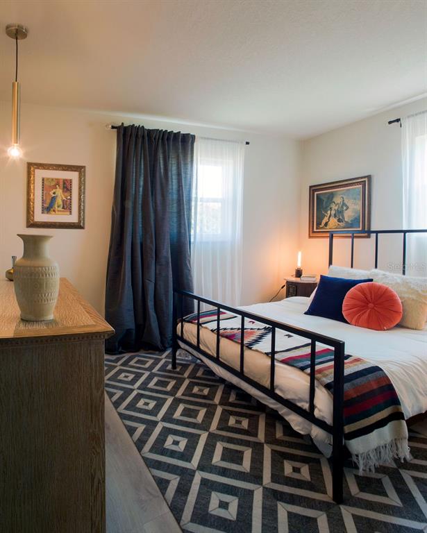 A bedroom features a metal bed frame, a geometric rug, and a wooden dresser — 6990 GREVILLA AVENUE S, SOUTH PASADENA, FL