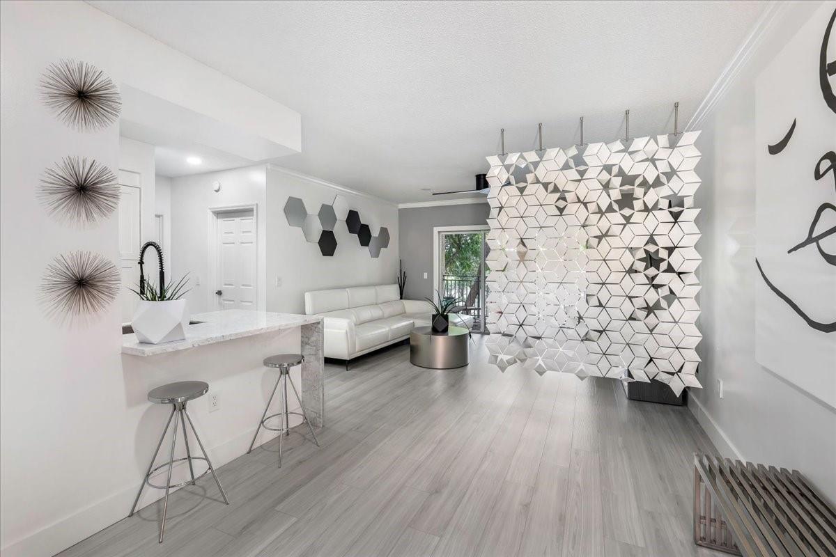 A modern living room features a geometric room divider, white sofa, and gray wood flooring — 2452 Centergate Drive # 202, Miramar FL 33025, MIRAMAR, FL