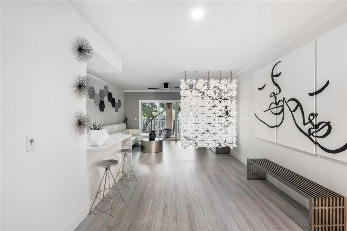 A modern living area features a geometric room divider, bar seating, and minimalist wall art — 2452 Centergate Drive # 202, Miramar FL 33025, MIRAMAR, FL