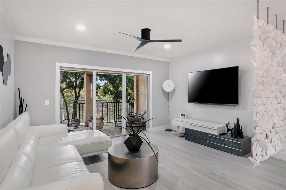 A modern living room features a white sectional sofa, a round coffee table, and a balcony — 2452 Centergate Drive # 202, Miramar FL 33025, MIRAMAR, FL