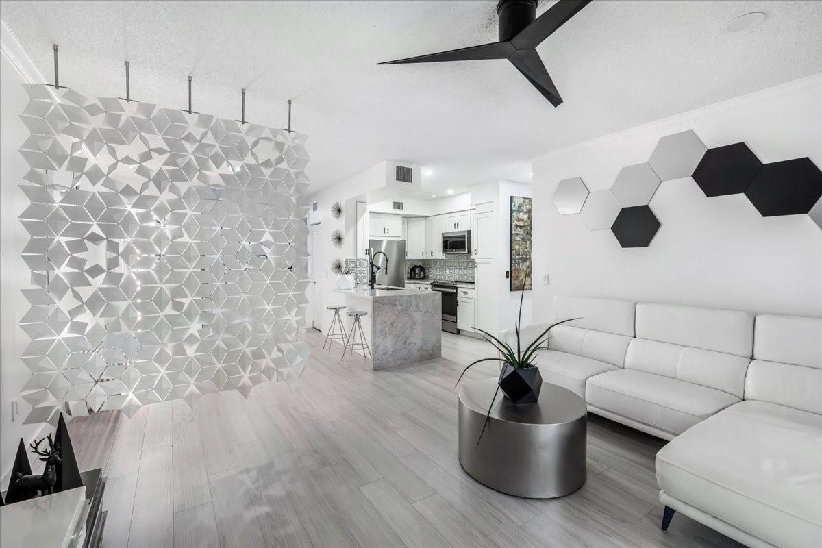 A modern living room features a white sectional sofa, geometric wall decor, and a room divider — 2452 Centergate Drive # 202, Miramar FL 33025, MIRAMAR, FL