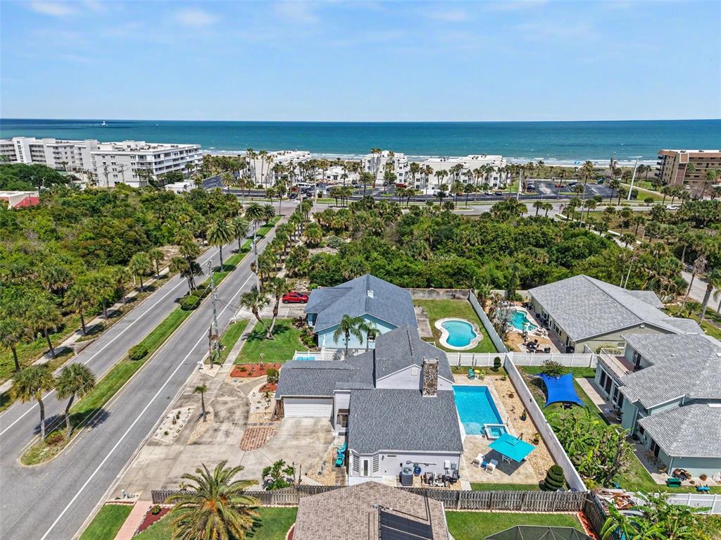 An aerial view shows a coastal neighborhood with houses, swimming pools, and the ocean beyond — 315 E CENTRAL BOULEVARD, CAPE CANAVERAL, FL