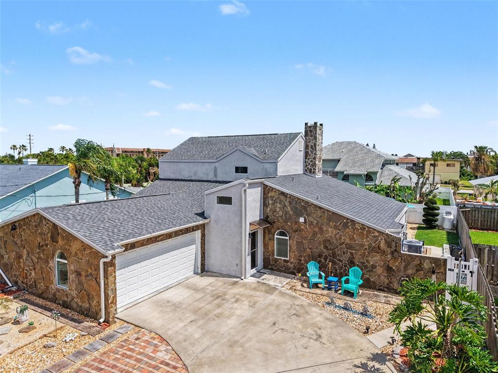 A two-story house features a stone facade, a white garage door, and a concrete driveway — 315 E CENTRAL BOULEVARD, CAPE CANAVERAL, FL