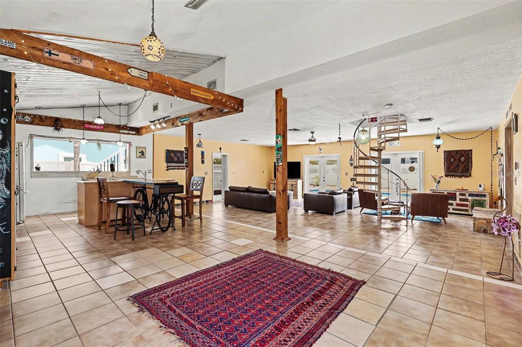 A spacious open-concept living area features tile flooring, a spiral staircase, and wooden ceiling beams — 315 E CENTRAL BOULEVARD, CAPE CANAVERAL, FL