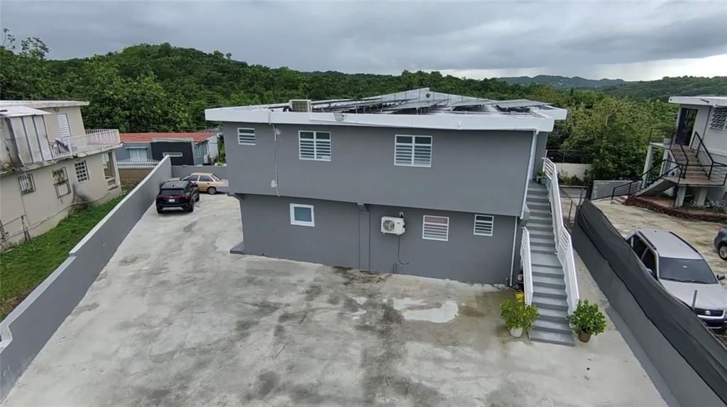 An exterior view of a two-story gray house with an outdoor staircase and solar panels — 8 . UNIT 183, TOA ALTA, PR