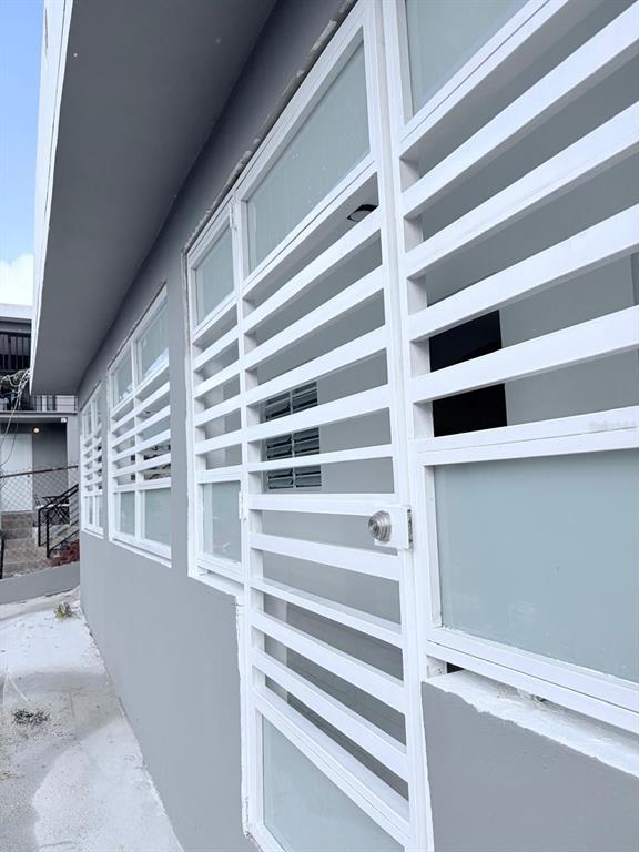 A side view of a gray building exterior featuring white-framed windows with security bars — 8 . UNIT 183, TOA ALTA, PR