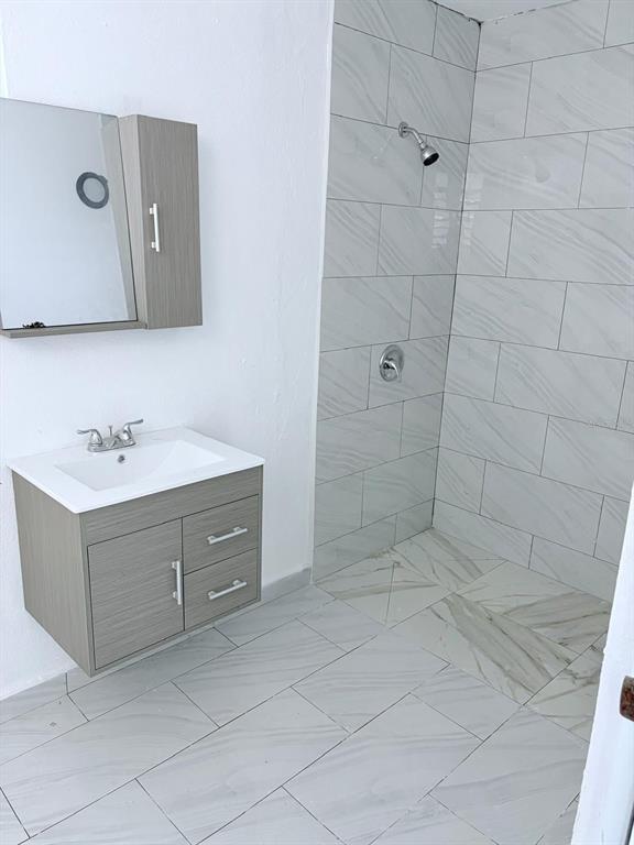 A bathroom features a gray vanity with a white sink, mirror, and a tiled shower — 8 . UNIT 183, TOA ALTA, PR
