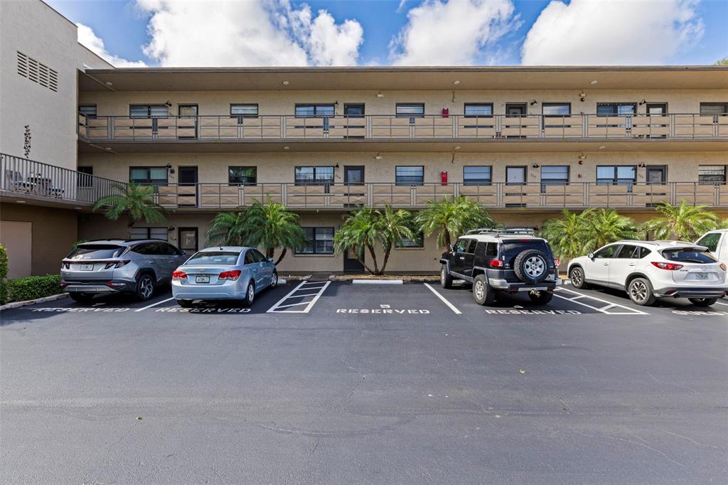 A three-story apartment building exterior with a parking lot featuring reserved spaces in front — 5975 TERRACE PARK DRIVE N UNIT 204, ST PETERSBURG, FL