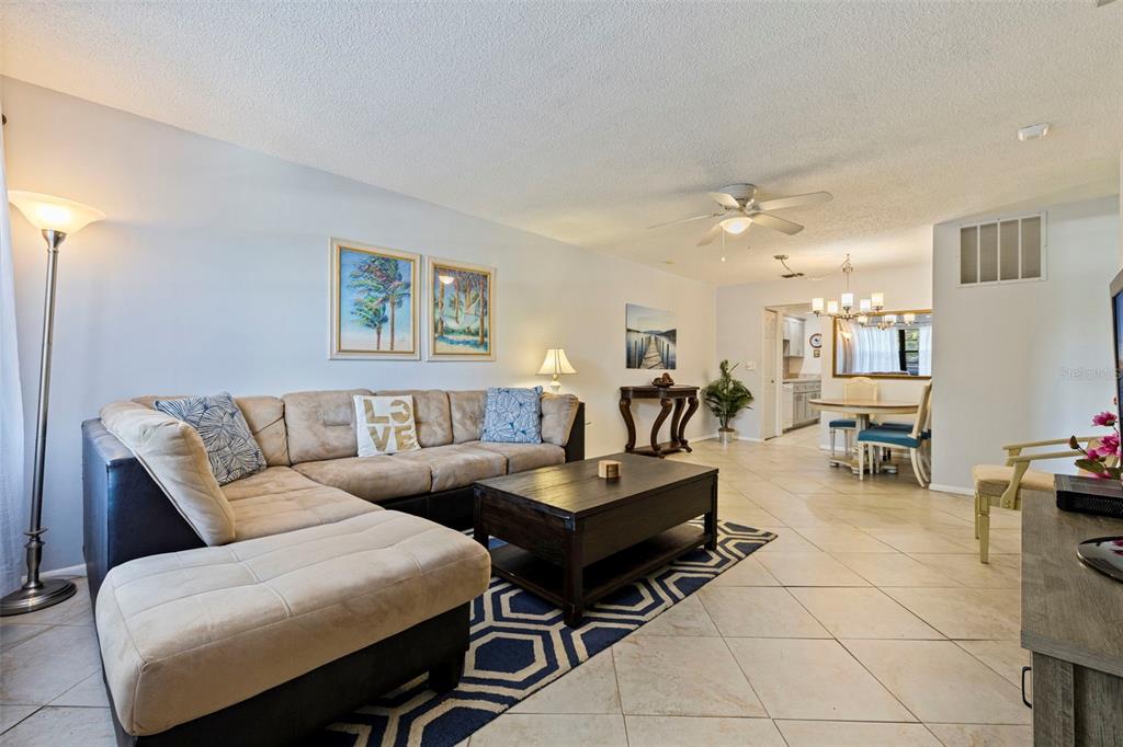 A living room with a beige sectional sofa, a dark coffee table, and tile flooring — 5975 TERRACE PARK DRIVE N UNIT 204, ST PETERSBURG, FL