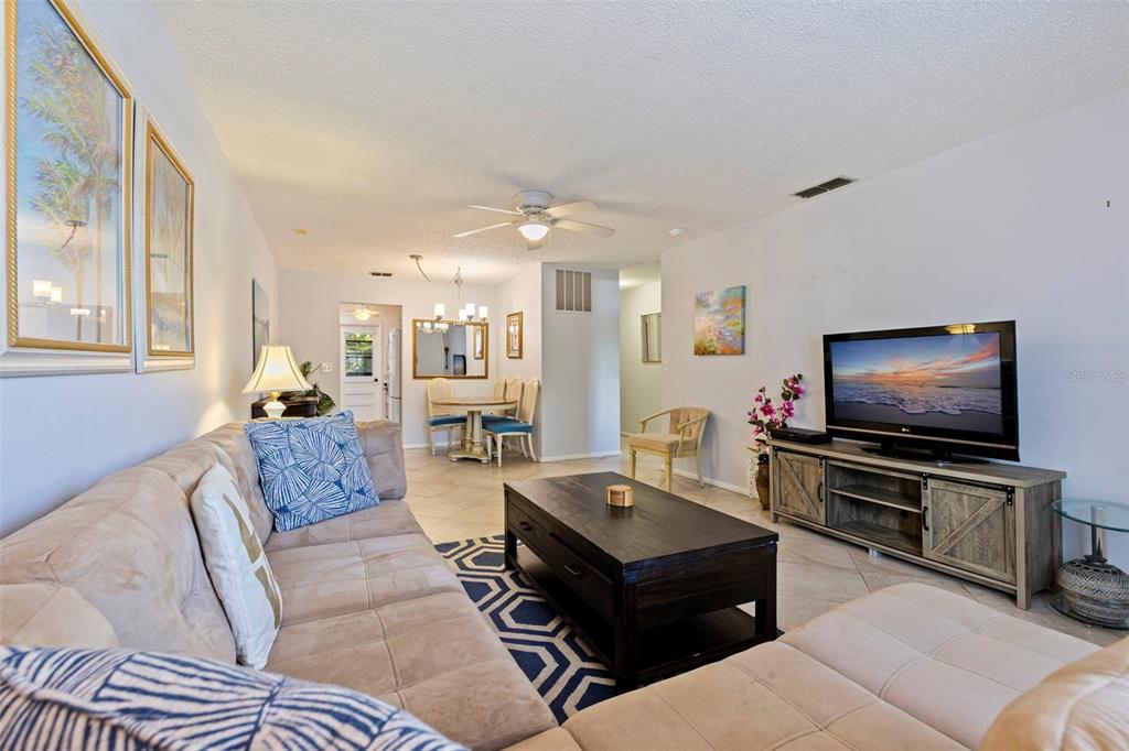 A living room with a beige sectional sofa, dark wood coffee table, and television console — 5975 TERRACE PARK DRIVE N UNIT 204, ST PETERSBURG, FL