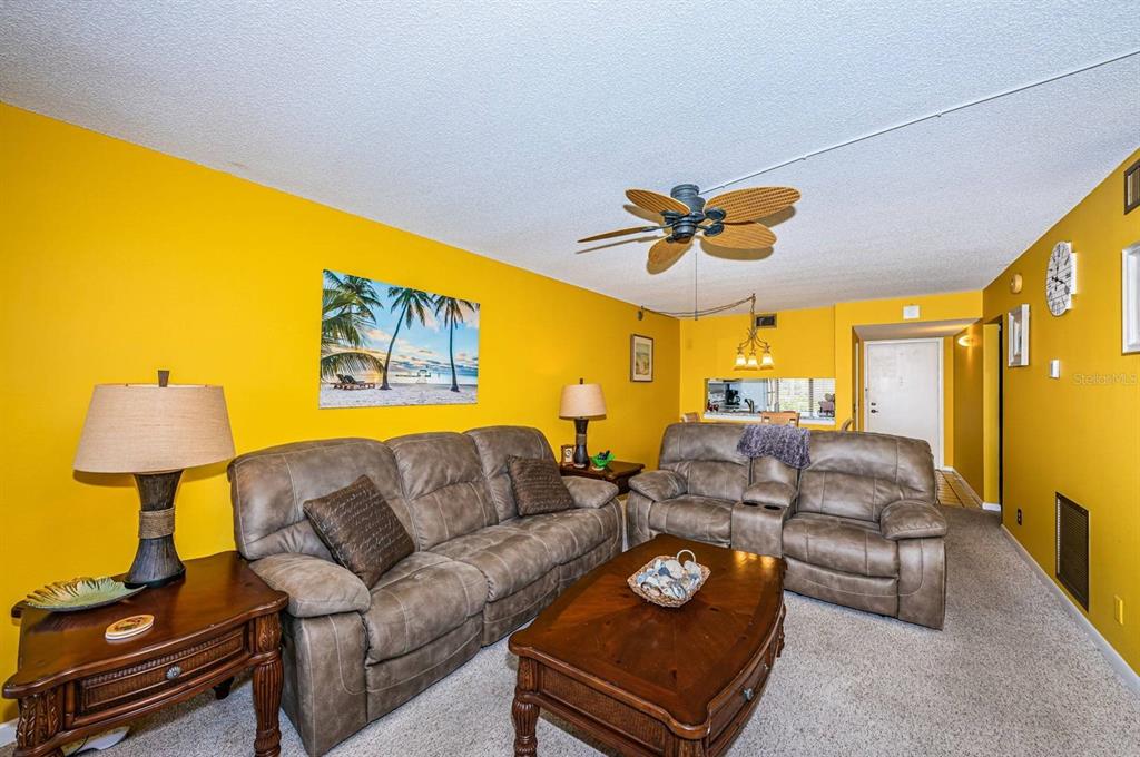 A living room features yellow walls, two brown leather sofas, and a wooden coffee table — 6273 BAHIA DEL MAR BOULEVARD UNIT 216, ST PETERSBURG, FL