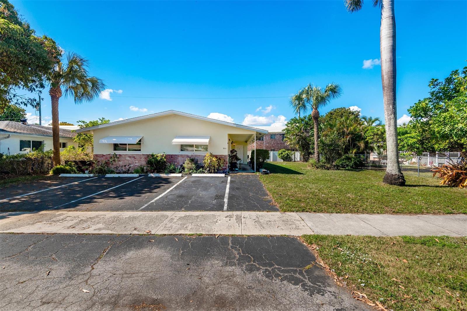 A single-story house with a brick and light-colored facade features a paved parking area — 321 SE 1st Avenue, Pompano Beach FL 33060, POMPANO BEACH, FL