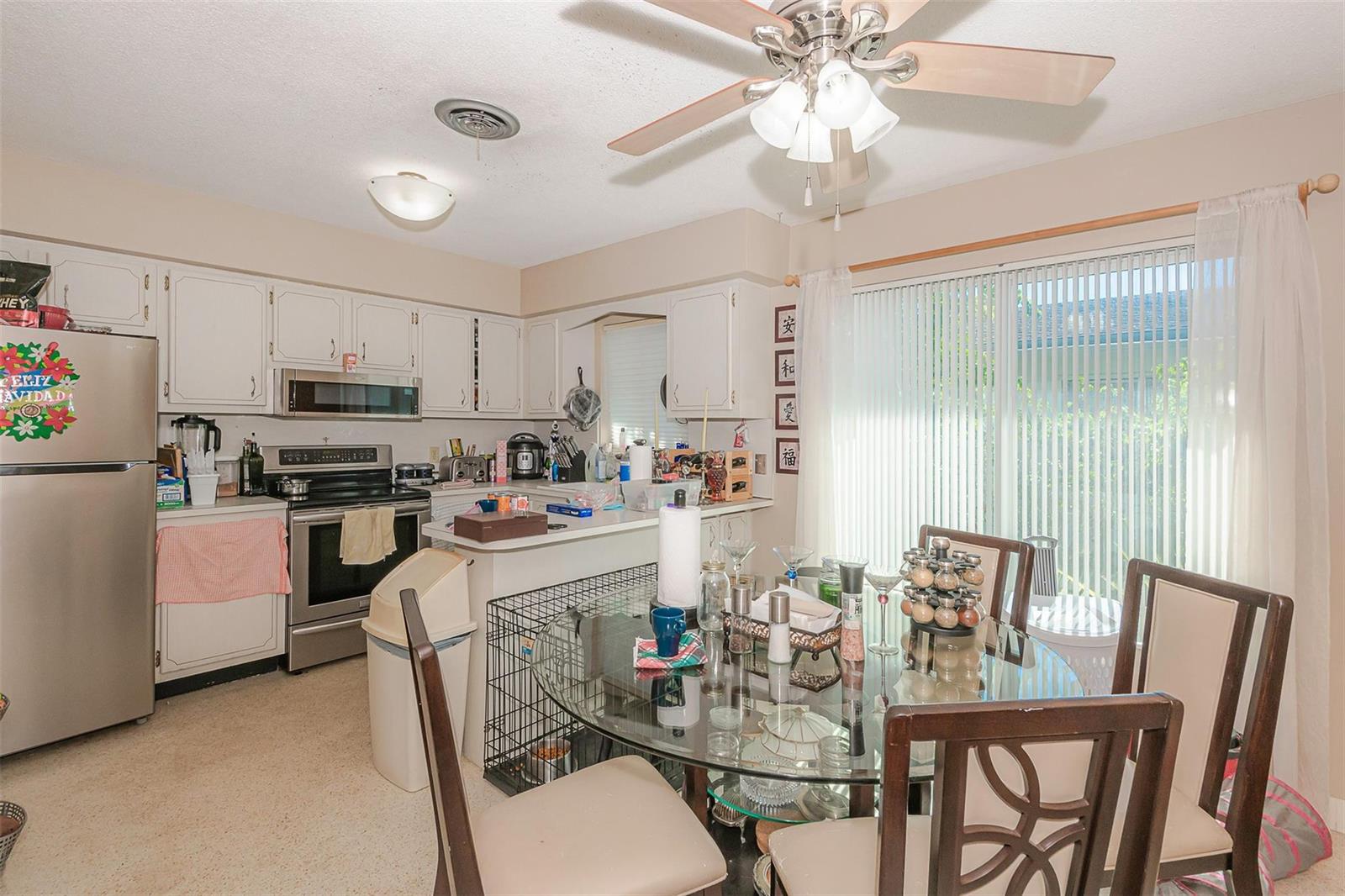 A kitchen features white cabinets, stainless steel appliances, a glass dining table, and sliding doors — 321 SE 1st Avenue, Pompano Beach FL 33060, POMPANO BEACH, FL
