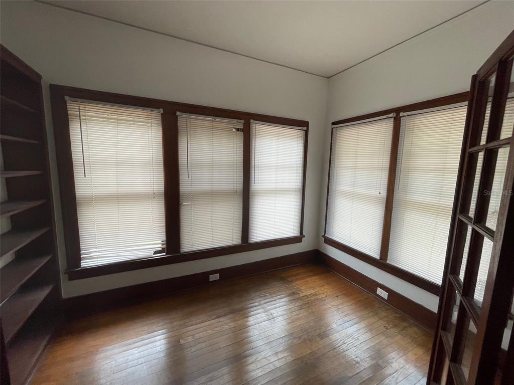 A room with hardwood floors, multiple windows with blinds, and built-in wooden shelving — 2635 W UNIVERSITY AVENUE, GAINESVILLE, FL