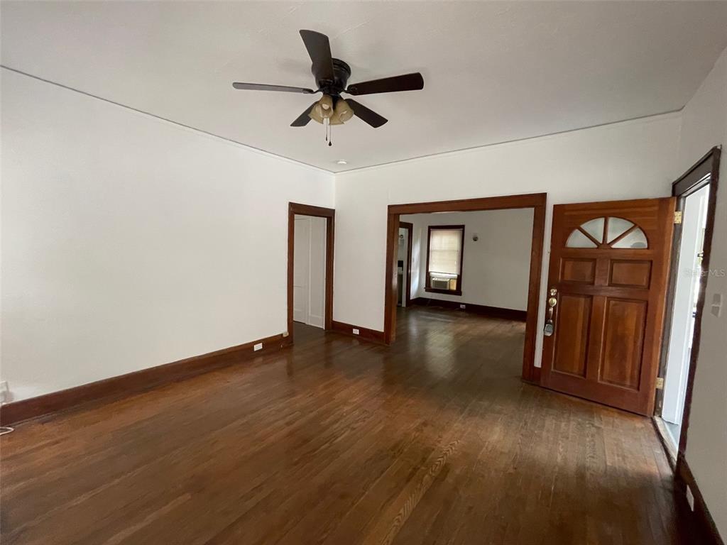 A living room features hardwood floors, white walls, wood trim, and a ceiling fan — 2635 W UNIVERSITY AVENUE, GAINESVILLE, FL