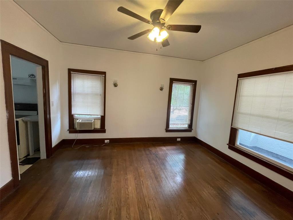 A room with hardwood floors, three windows with blinds, and a ceiling fan — 2635 W UNIVERSITY AVENUE, GAINESVILLE, FL