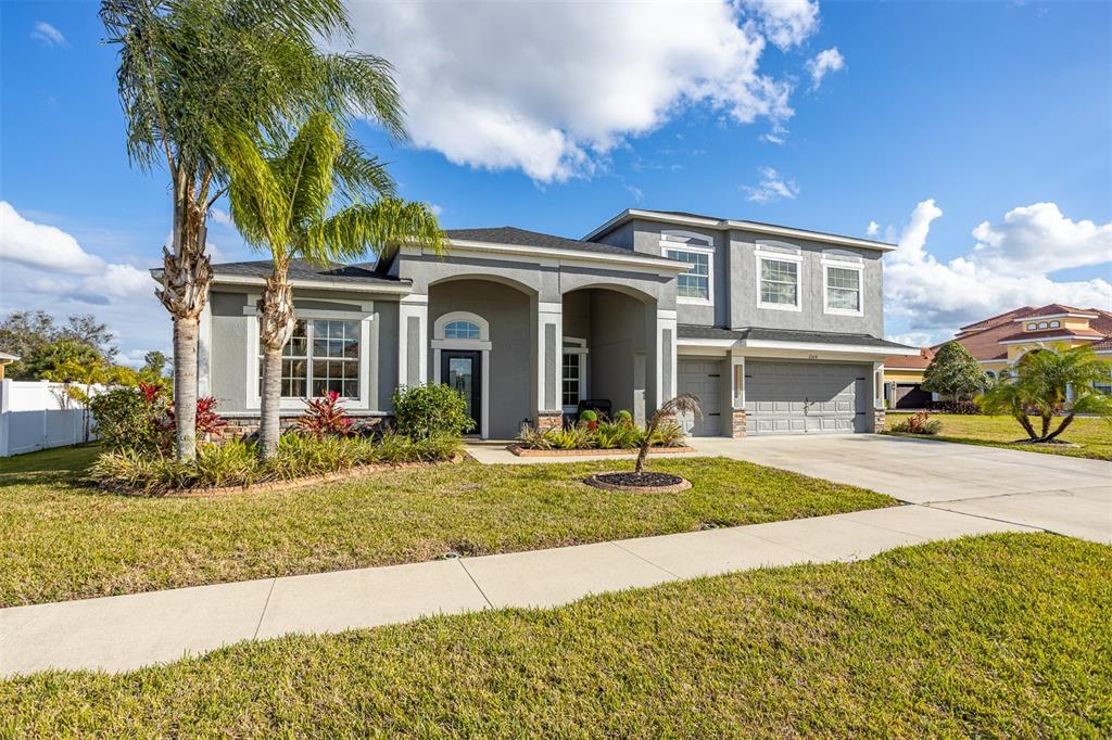 A two-story gray house with a palm tree, a concrete driveway, and a front lawn — 2504 CUMBERLAND CLIFF DRIVE, RUSKIN, FL
